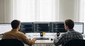 Two focused young male programmers working together on multiple computer screens with code in modern office environment Royalty Free Stock Photo