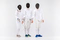 The two men and woman wearing fencing suit with sword against gray Royalty Free Stock Photo