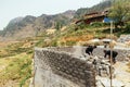 Two men workers building house by autoclaved lightweight concrete with villages and mountain in the background in summer.