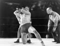 Two men wrestling with referee making a call in the background Royalty Free Stock Photo