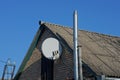 Two metal chimney pipes and a white satellite dish in the attic of a rural house under a slate roof Royalty Free Stock Photo