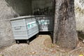 Two metal containers placed in a corner of a yard surrounded with high bricked fence.