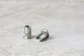 Two metal grey river nuts for hard internal thread for thin units on left part of oblong horizontal shot textured cement