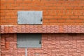 Two metal rectangular hatches in a red brick wall