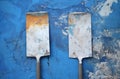 two metal spatulas on a blue surface