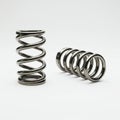Two metallic helical springs are displayed on a plain white background. One spring Royalty Free Stock Photo