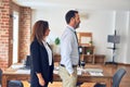 Two middle age business workers standing working together in a meeting at the office looking to side, relax profile pose with Royalty Free Stock Photo