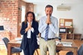 Two middle age business workers standing working together in a meeting at the office praying with hands together asking for