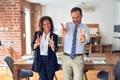 Two middle age business workers standing working together in a meeting at the office smiling looking to the camera showing fingers Royalty Free Stock Photo