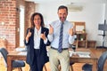 Two middle age business workers standing working together in a meeting at the office success sign doing positive gesture with Royalty Free Stock Photo