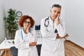 Two middle age doctors at medical clinic thinking looking tired and bored with depression problems with crossed arms Royalty Free Stock Photo