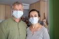 Two middle aged person with protective mask at home due to coronavirus quarantine