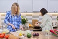 Two middle aged women cooking together at home in kitchen Royalty Free Stock Photo