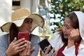 Two 2 middle aged women having fun sharing thoughts and stories holding smart phone.