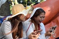 Two 2 middle aged women having fun sharing thoughts and stories holding smart phone.