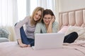 Two middle aged women having rest sitting together at home on bed, looking in laptop screen. Royalty Free Stock Photo