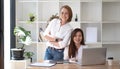 Two middle-aged women are looking at the camera while sitting on a desk in the office. female executives working in the office Royalty Free Stock Photo