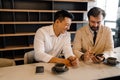 Two middleaged businessmen look in phone and discuss by table