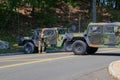 Two military Jeep vehicles are seen blocking a small tree lined country road. A military police officer with a gun is getting out Royalty Free Stock Photo