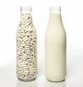 Two milk bottles one filled with milk the other filled with lactase pills