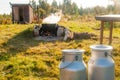 Two milk cans and a boiling kettle in an old landscape. Royalty Free Stock Photo