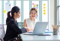 Two millennial Asian young beautiful professional successful businesswoman colleagues sitting smiling in meeting room having funny Royalty Free Stock Photo