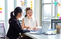 Two millennial Asian young beautiful professional successful businesswoman colleagues sitting smiling in meeting room having funny Royalty Free Stock Photo