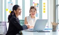 Two millennial Asian young beautiful professional successful businesswoman colleagues sitting smiling in meeting room having funny Royalty Free Stock Photo