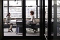 Two millennial businesswomen meeting for a job interview, full length, seen through glass wall Royalty Free Stock Photo