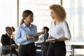 Two millennial ethnic women workers exchange opinions in private conversation