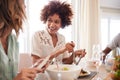 Two millennial girlfriends talking at the table and serving food during lunch with friends, close up Royalty Free Stock Photo