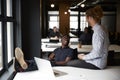 Two millennial male creatives talking at a desk in a casual  open plan office, close up Royalty Free Stock Photo