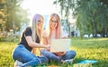 Two millennial university student girls sitting in the grass in campus - Young smiling friends using laptop and downloading Royalty Free Stock Photo