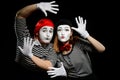 Two mimes leaning on imaginary wall with hands in white gloves Royalty Free Stock Photo