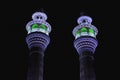 Two Minarets of an Iranian mosque are illuminated by colorful light at night.