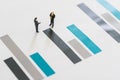 Two miniature businessmen speak and handshake stand on the bar chart, as commitment, partnership Royalty Free Stock Photo