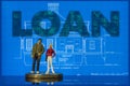 Two miniature figures standing on a house blueprint as if discussing the plans. Concept Home Loan macro Royalty Free Stock Photo