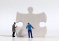 Two miniature men carrying puzzle piece.
