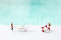 Two miniature worker moving plastic white beach chair and life buoy at the swimming pool edge over blurred blue water Royalty Free Stock Photo