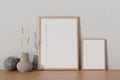 Two minimal picture frames mockup and a ceramic vase on a wooden tabletop against the white wall Royalty Free Stock Photo