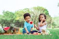 Two mixed race caucasian little cute children kids sitting, playing in outdoor green park for picnic, eating fruit, watermelon and Royalty Free Stock Photo