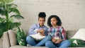 Two mixed race curly girl friends sitting on the couch and watch very scary movie on TV and eat popcorn at home Royalty Free Stock Photo