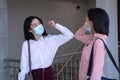 Two businesswomen wearing face masks greeting each other by touching elbows at modern office