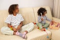 Two mixed race girls are sitting on a couch and playing with toys, symbolizing eco friendly toy, occupation and learning Royalty Free Stock Photo