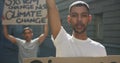 Two mixed race men on a protest march holding placards raising hands and shouting