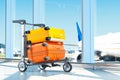 Two modern coloured blank suitcases with airport on background, 3d rendering.