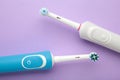 Two Modern electric toothbrushes on purple background.