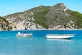 Two modern plastic motorboats anchored near the beach in the shallow clear blue water of the warm mediterranean sea