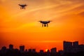 Two modern Remote Control Air Drones Fly with action cameras in dramatic orange sunset sk Royalty Free Stock Photo