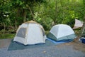Two Modern Tents Pitched by a River in a Shady Forest Campsite Royalty Free Stock Photo